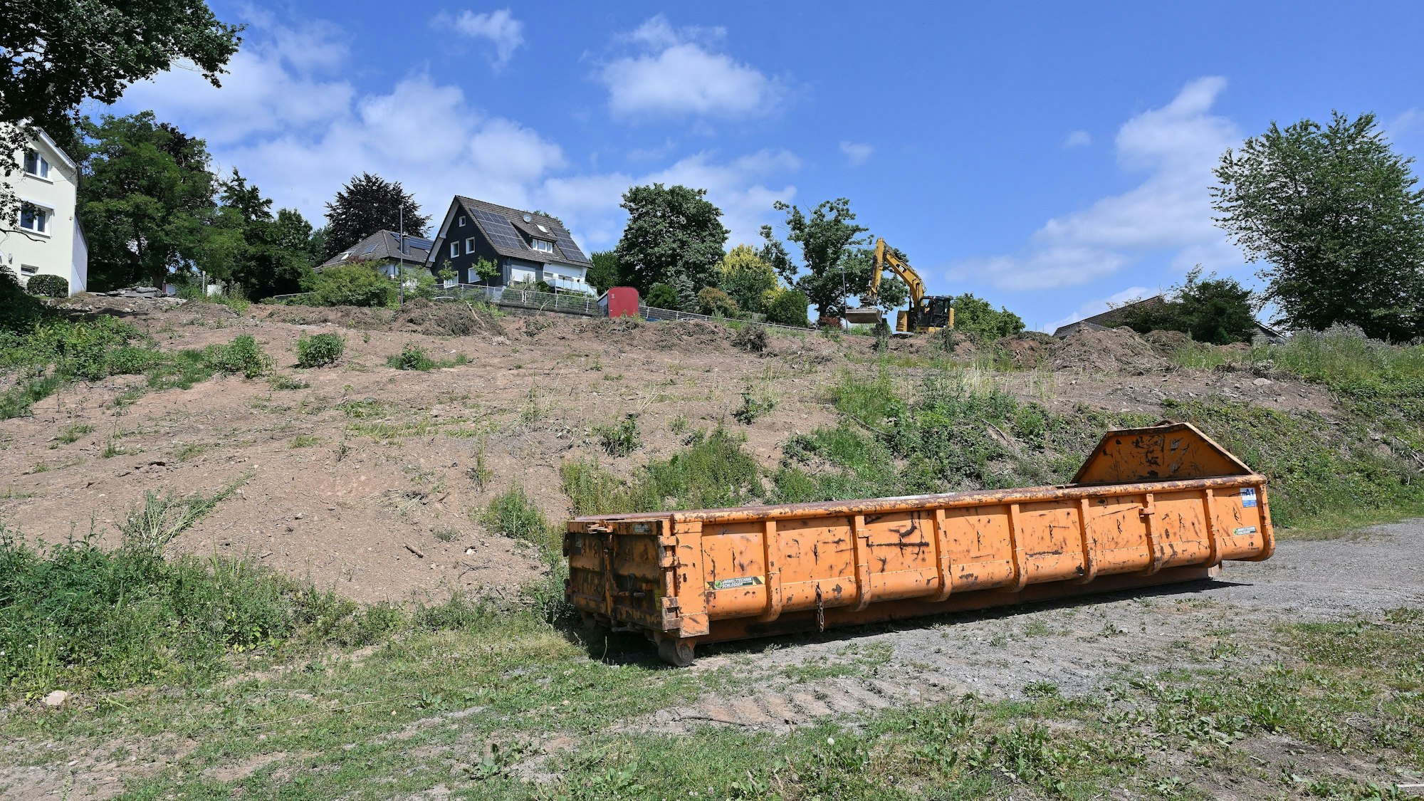 Auf dem Grundstück, auf dem gebaut werden soll, steht ein orangefarbener Container.
