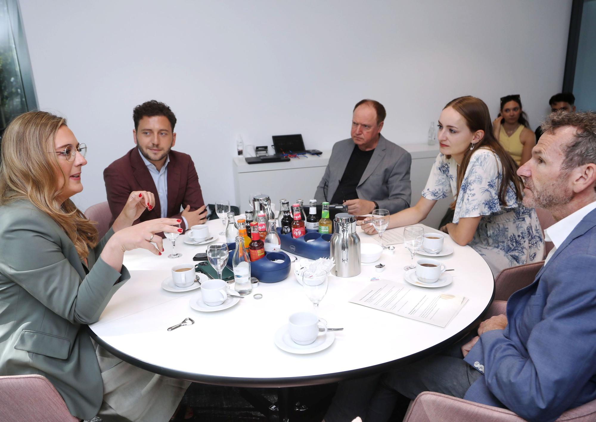 Die Gesprächsrunde ist an einem runden Tisch zu sehen.