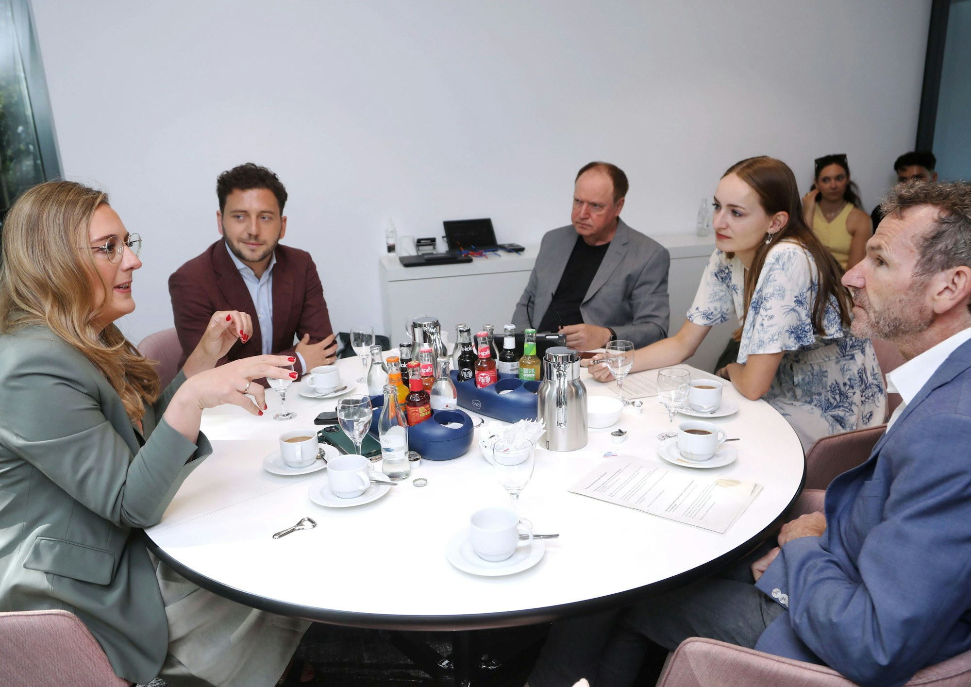 Die Gesprächsrunde ist an einem runden Tisch zu sehen.