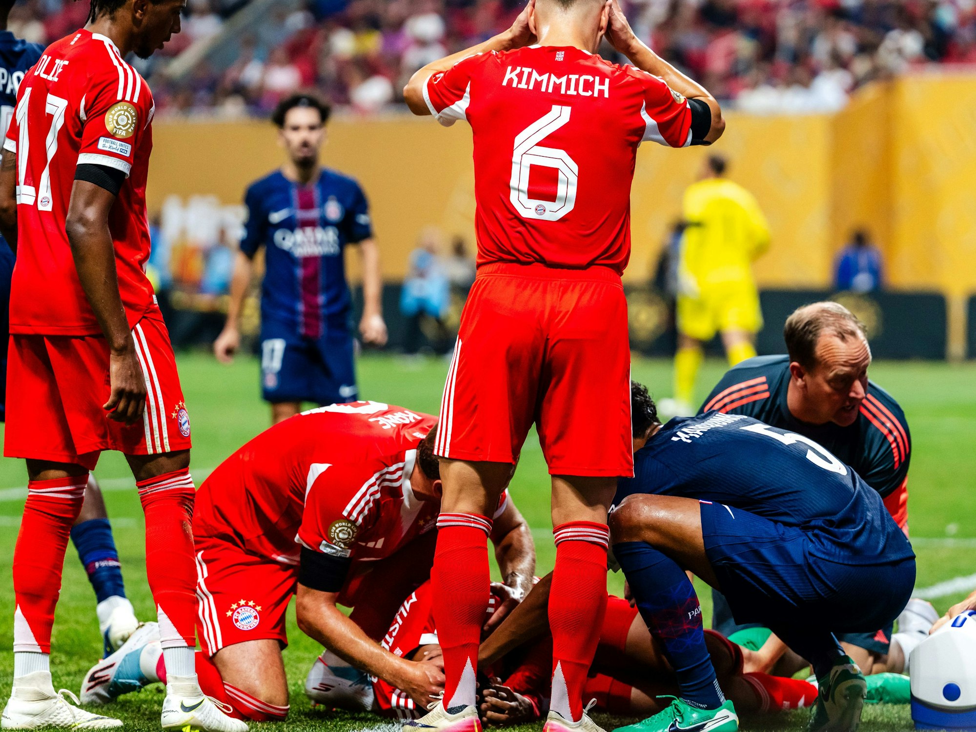 Joshua Kimmich und andere Spieler beider Mannschaften reagieren auf die Verletzung von Jamal Musiala, der verletzt am Boden liegt.