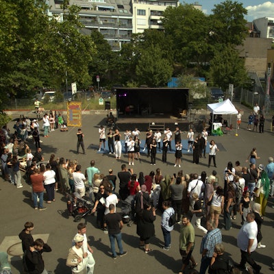 Schüler und Lehrer stehen versammelt auf dem Schulfhof der Peter-Ustinov-Realschule in Nippes, anlässlich des 125-jähriges Bestehens.