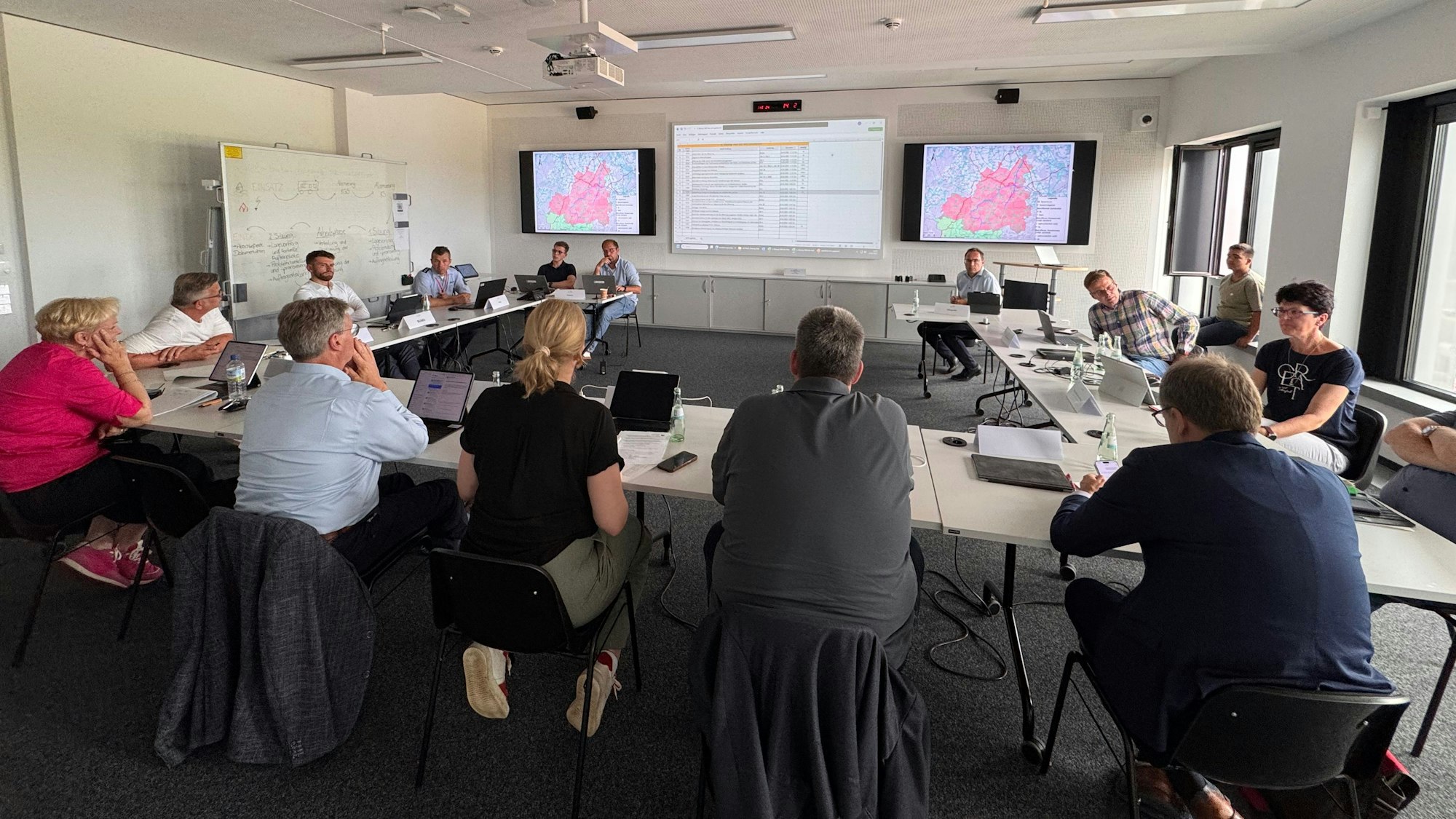 Menschen sitzen im Lagezentrum beisammen und besprechen sich.