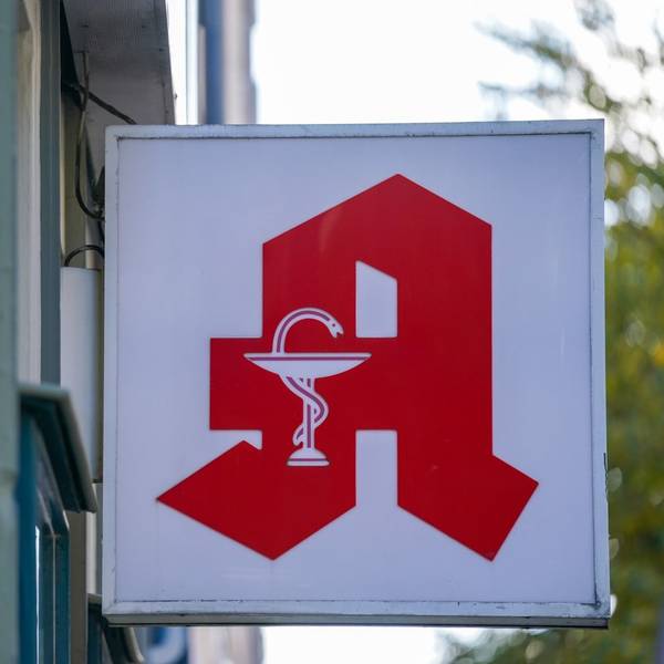 Ein Apotheken-Logo hängt an der Eingangsfassade einer Apotheke.