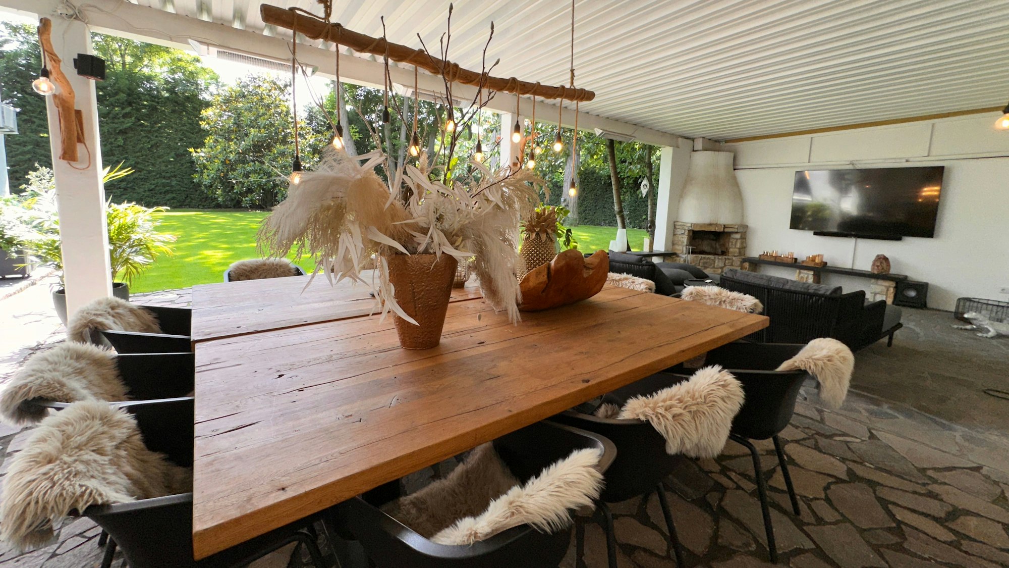 In einem großen luftigen Raum steht ein massiver Holztisch mit elf Stühlen, der Blick geht in den Garten.