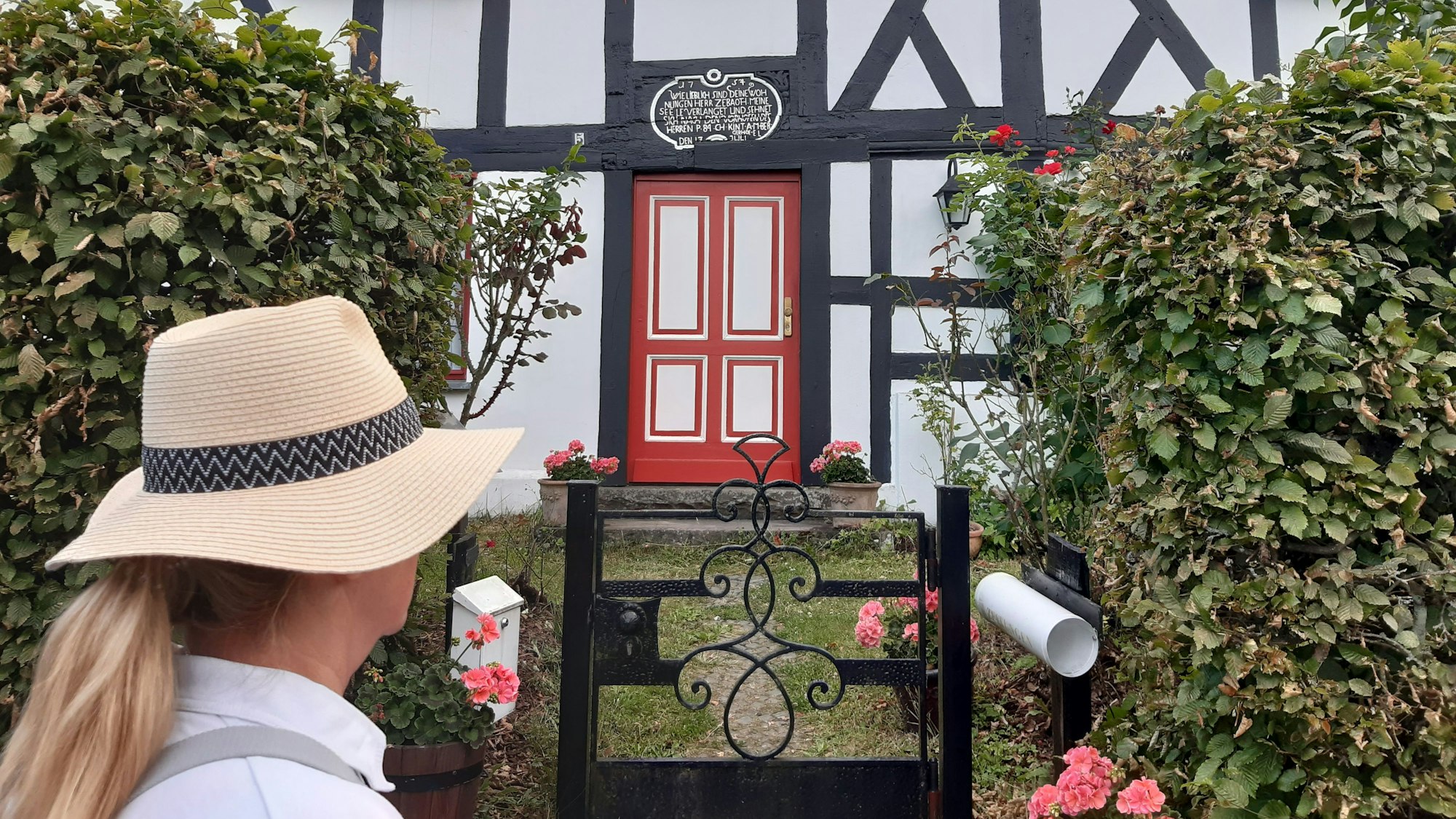 Eine Frau blickt auf die Fassade eines Fachwerkhauses.