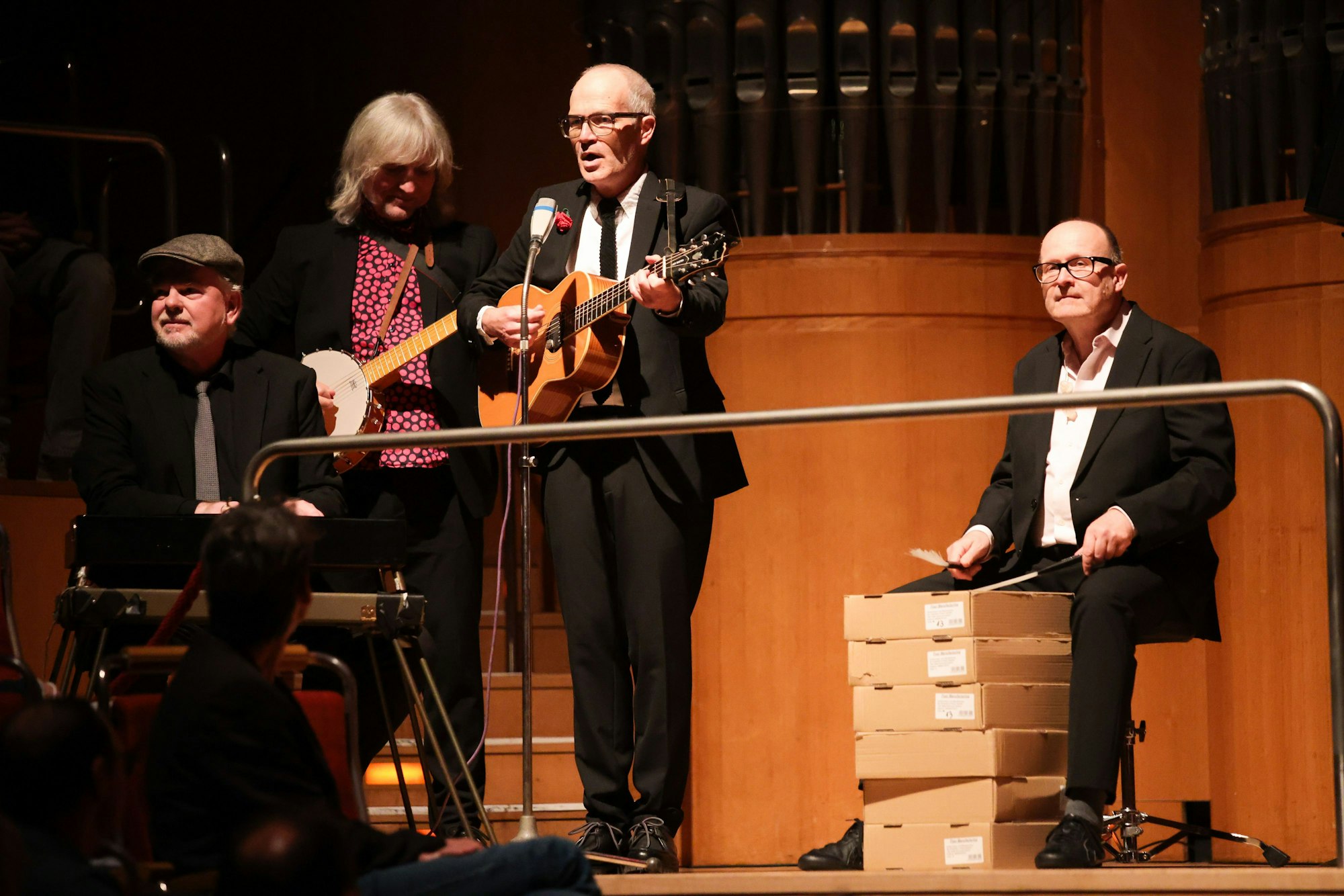 Christian Wübben (rechts) streicht mit dem Schlagzeugbesen auf gestapelte Schachteln, Markus Berges singt zur akustischen Gitarre, Ekki Maas zupft ein Banjo, Wolfgang Proppe sitzt mit seinem Mini-Keyboard beinahe im Publikum.
