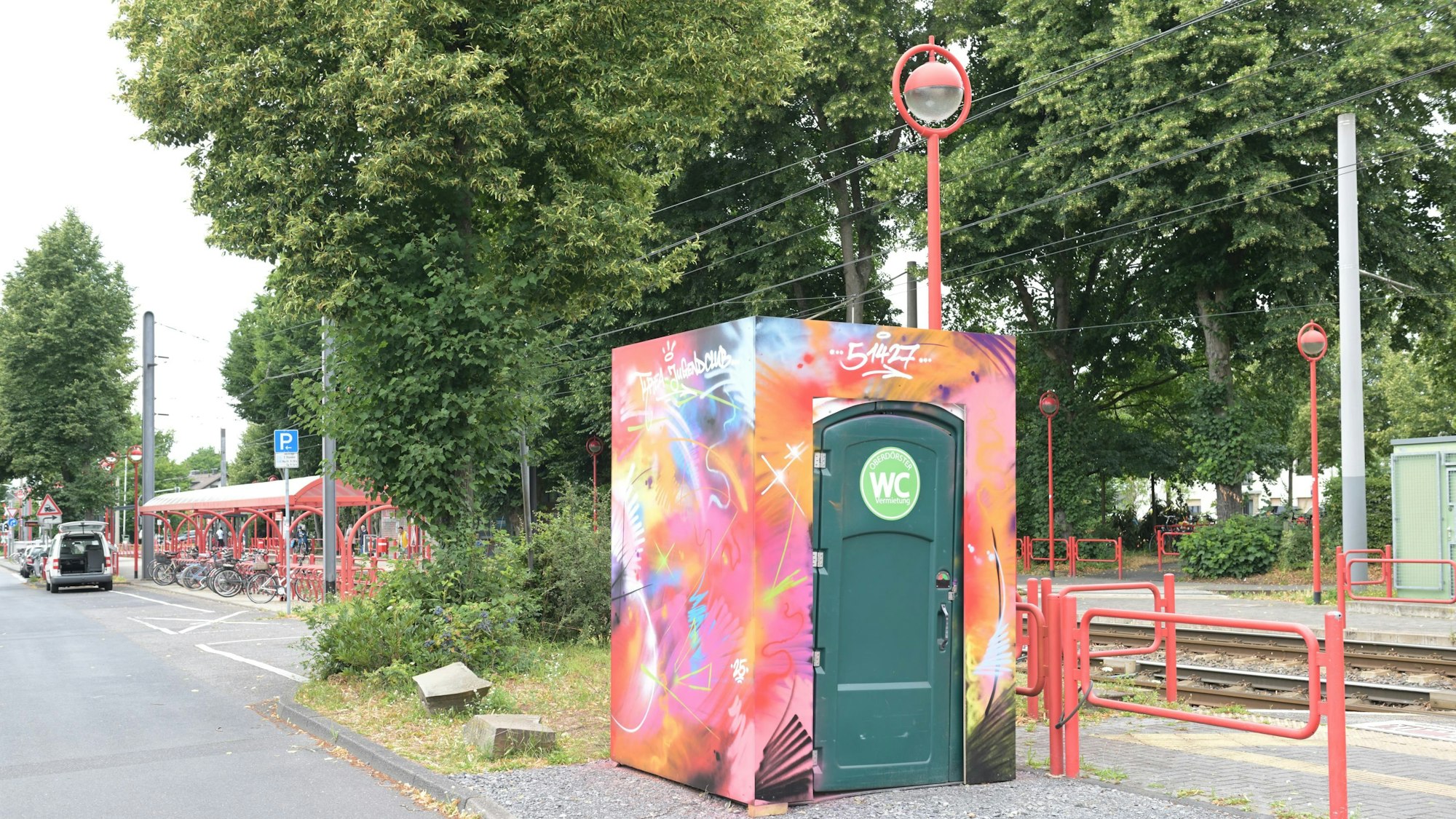 Man sieht das Klo-Häuschen, gestaltet mit grellen Farben.