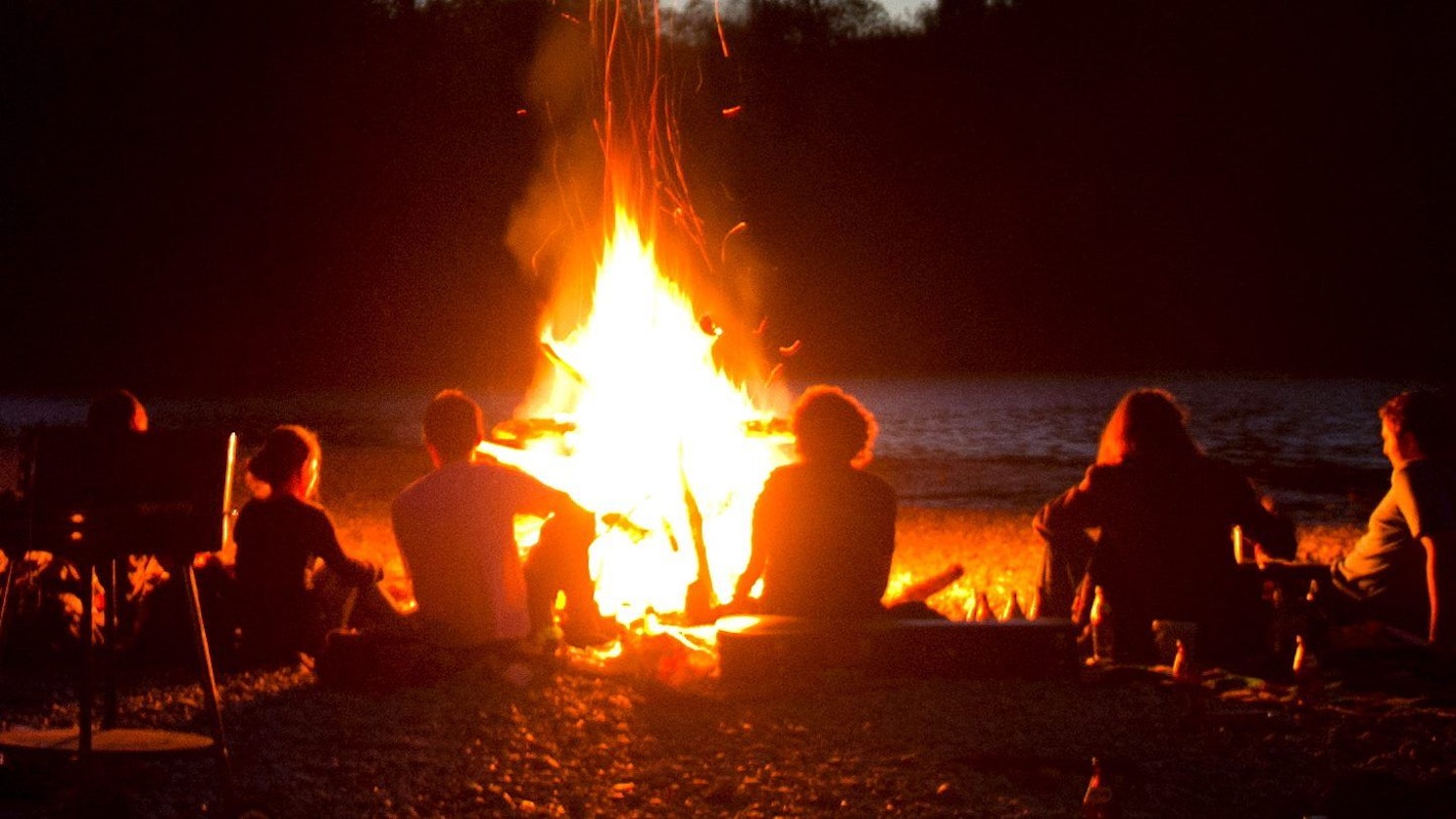 Junge Leute sitzen um ein Lagerfeuer. (Symbolbild)