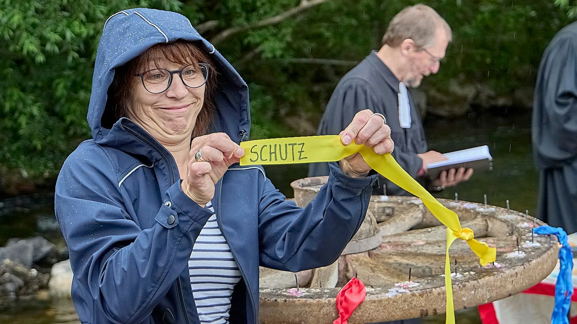 Eine Frau hält ein Band hoch, auf dem der Schriftzug „Schutz“ zu erkennen ist.