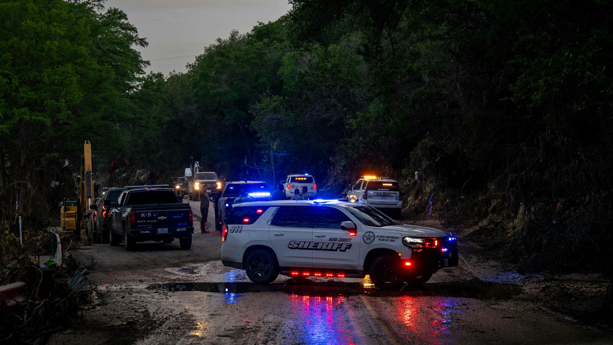 Ein Polizeiwagen sperrt eine verschlammte Straße ab.