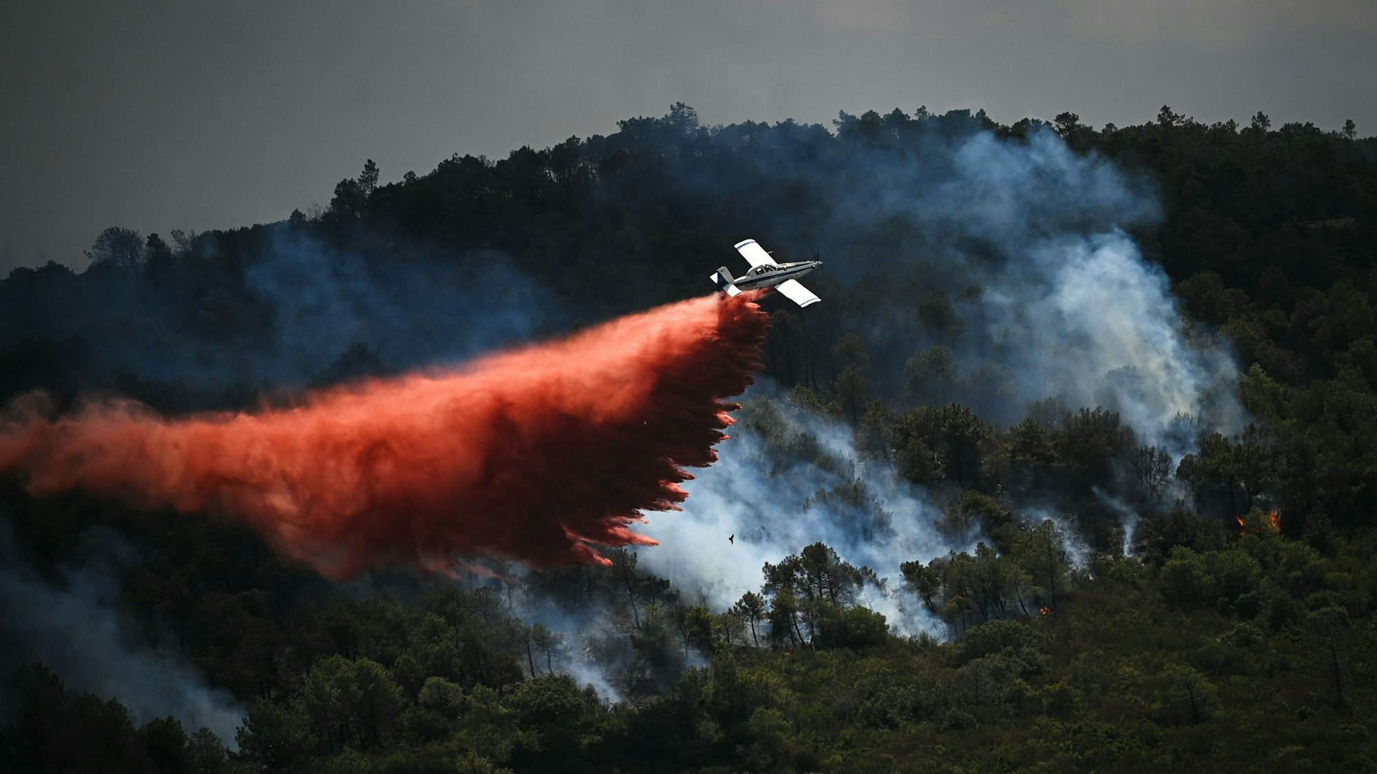 Ein Löschflugzeug wirft in der Nähe der Stadt Narbonne im Südwesten Frankreichs Löschmittel über einem Waldbrand ab.