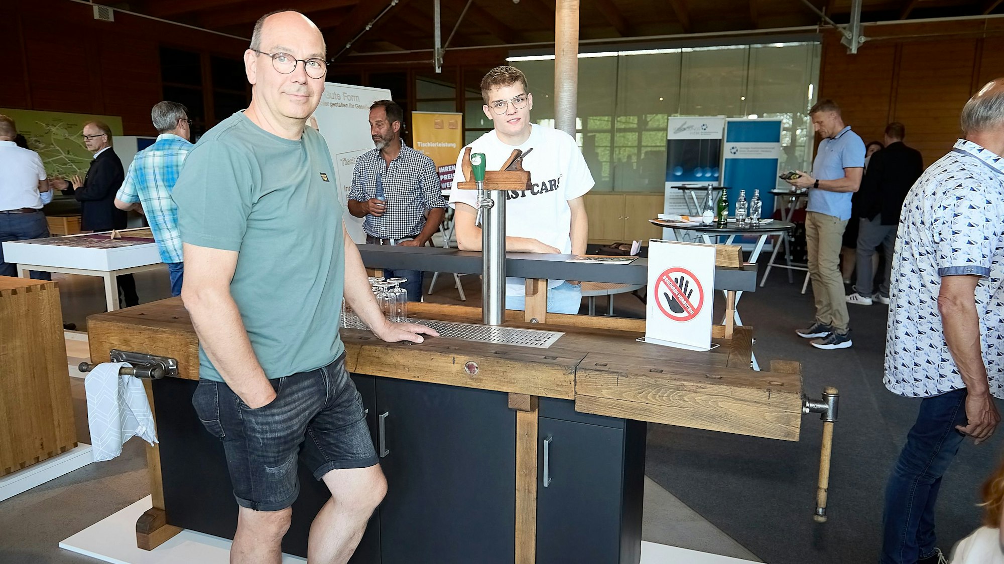 Zwei Männer stehen an einer Theke, die aus einer alten Hobelbank aus Holz gebaut wurde.
