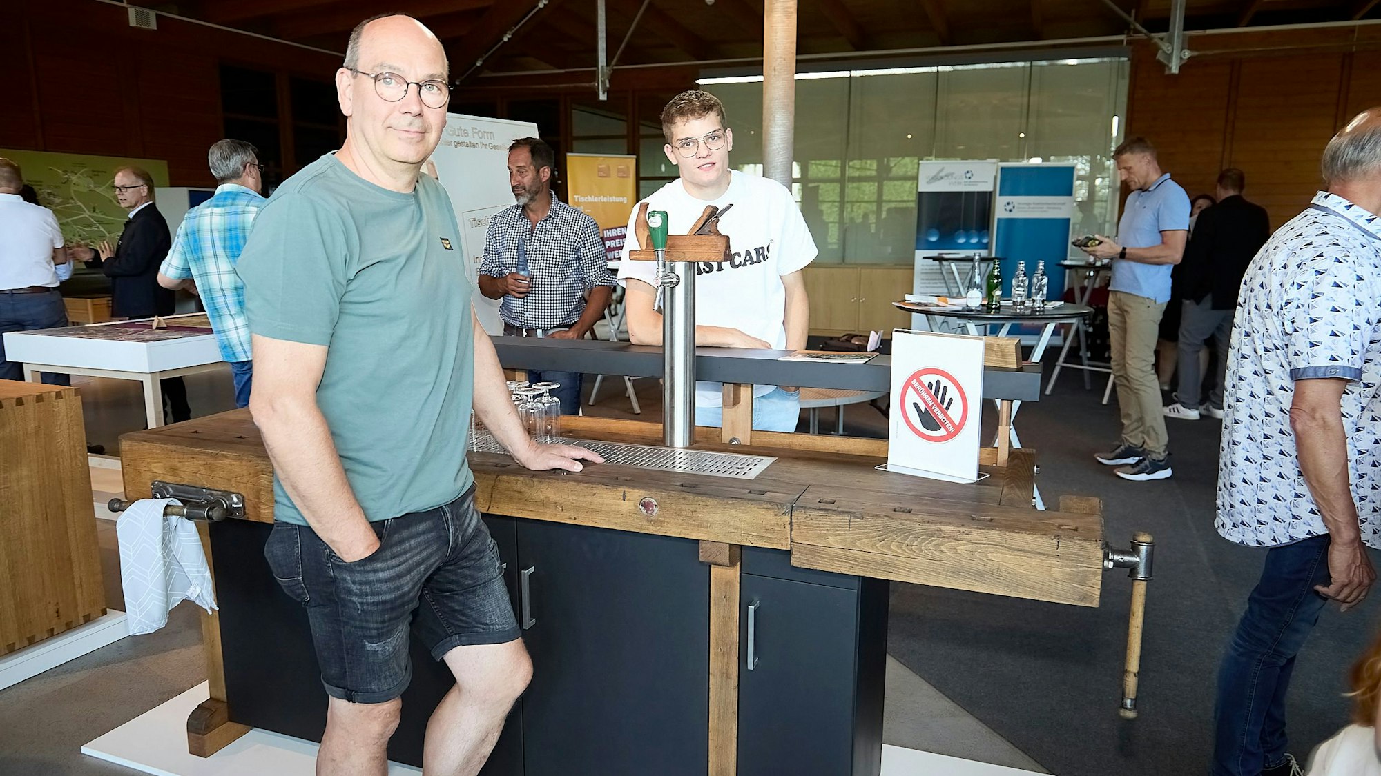 Zwei Männer stehen an einer Theke, die aus einer alten Hobelbank aus Holz gebaut wurde.