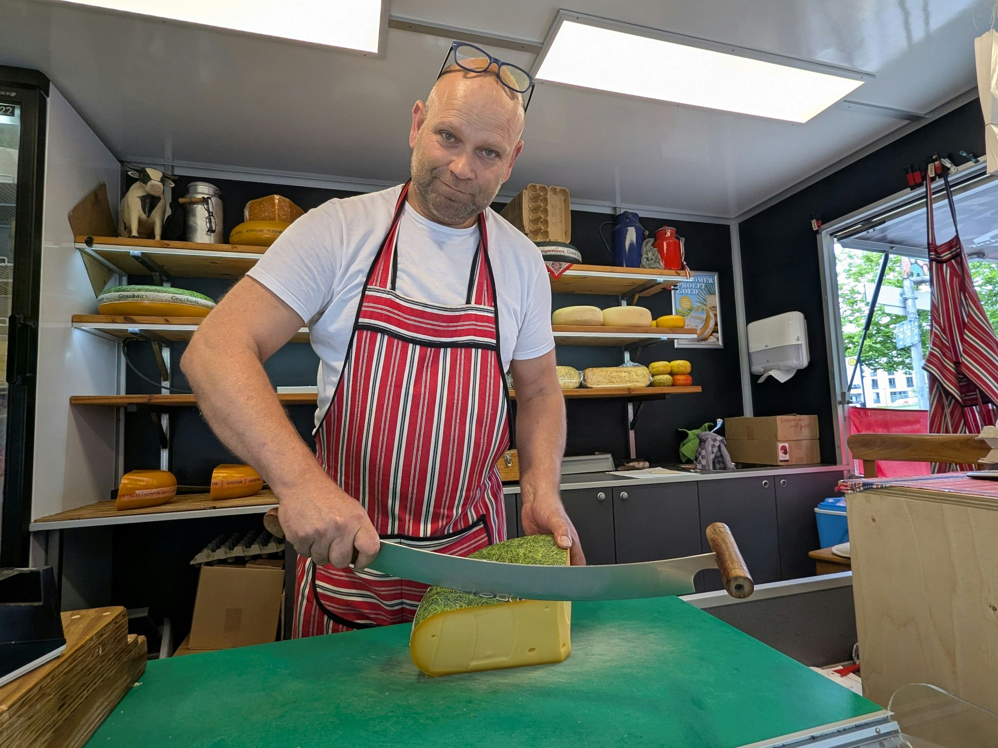 Käsehändler Gerard Beckers schneidet an seinem Stand mit einem großen Messer ein Stück von einem Gouda ab.