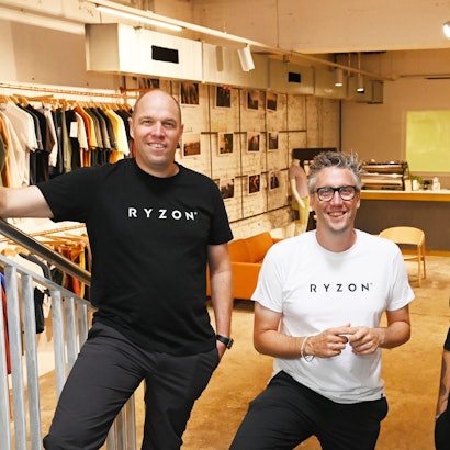Markus Konrad, Marius Konrad und Fabian Jung stehen im Ryzon-Store im Belgischen Viertel. Im Hintergrund ist der Laden mit ausgestellten Kleidungsstücken und einer Espressobar zu sehen.
