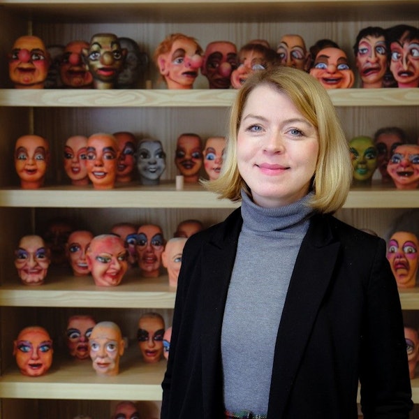 Frau Marx ist vor einem Regal mit Puppenköpfen im Porträt zu sehen.