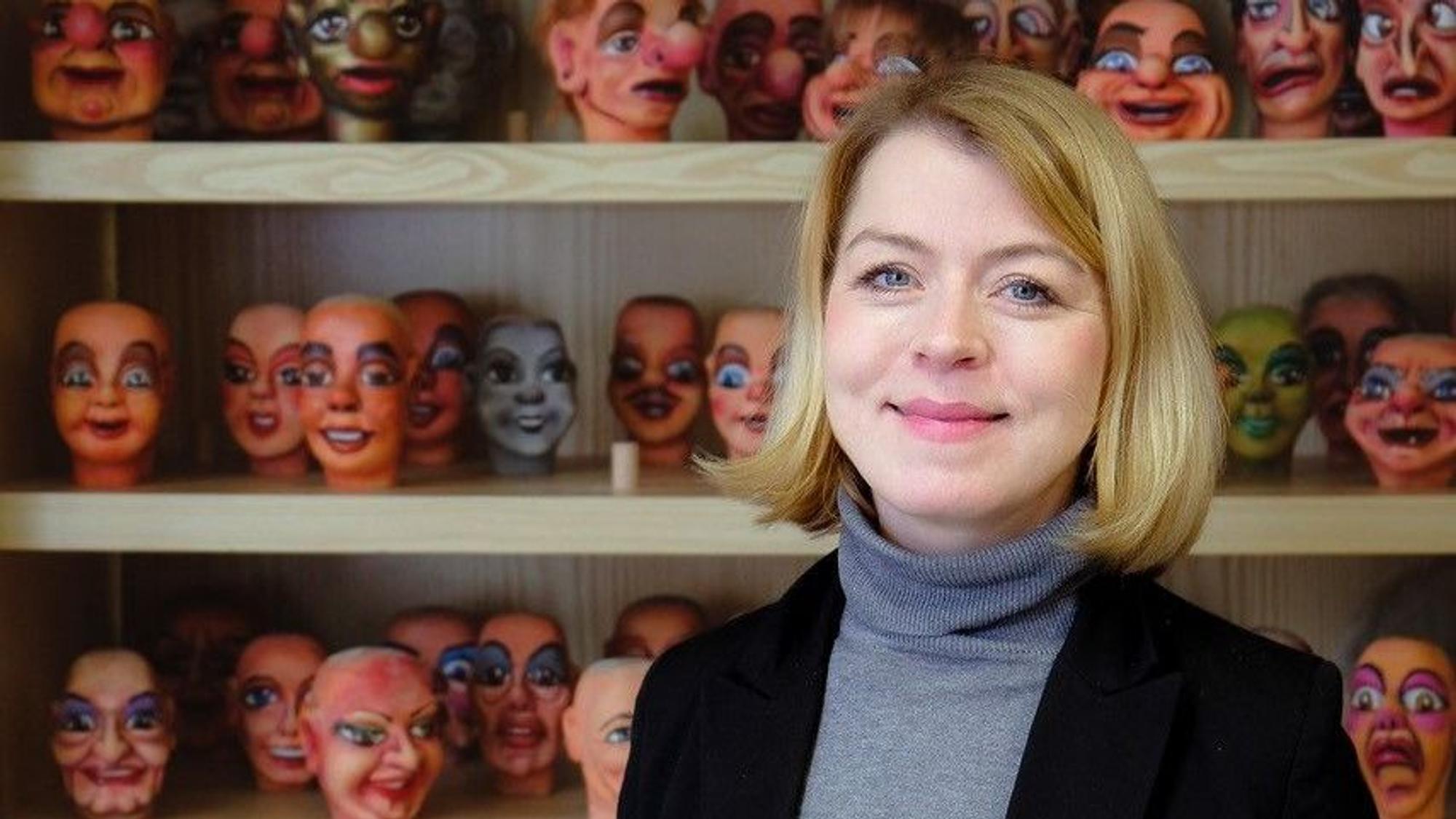 Frau Marx ist vor einem Regal mit Puppenköpfen im Porträt zu sehen.