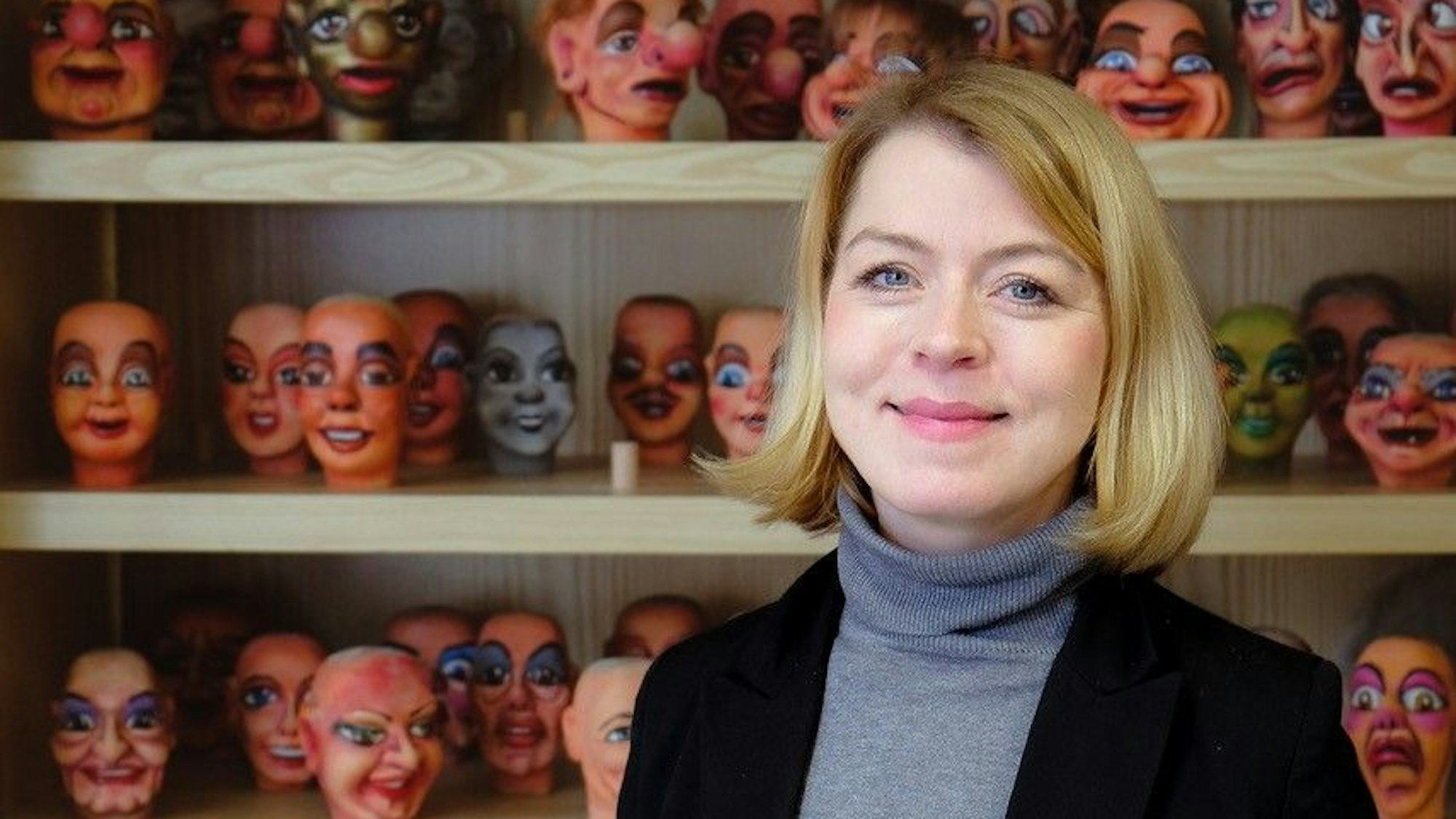 Frau Marx ist vor einem Regal mit Puppenköpfen im Porträt zu sehen.