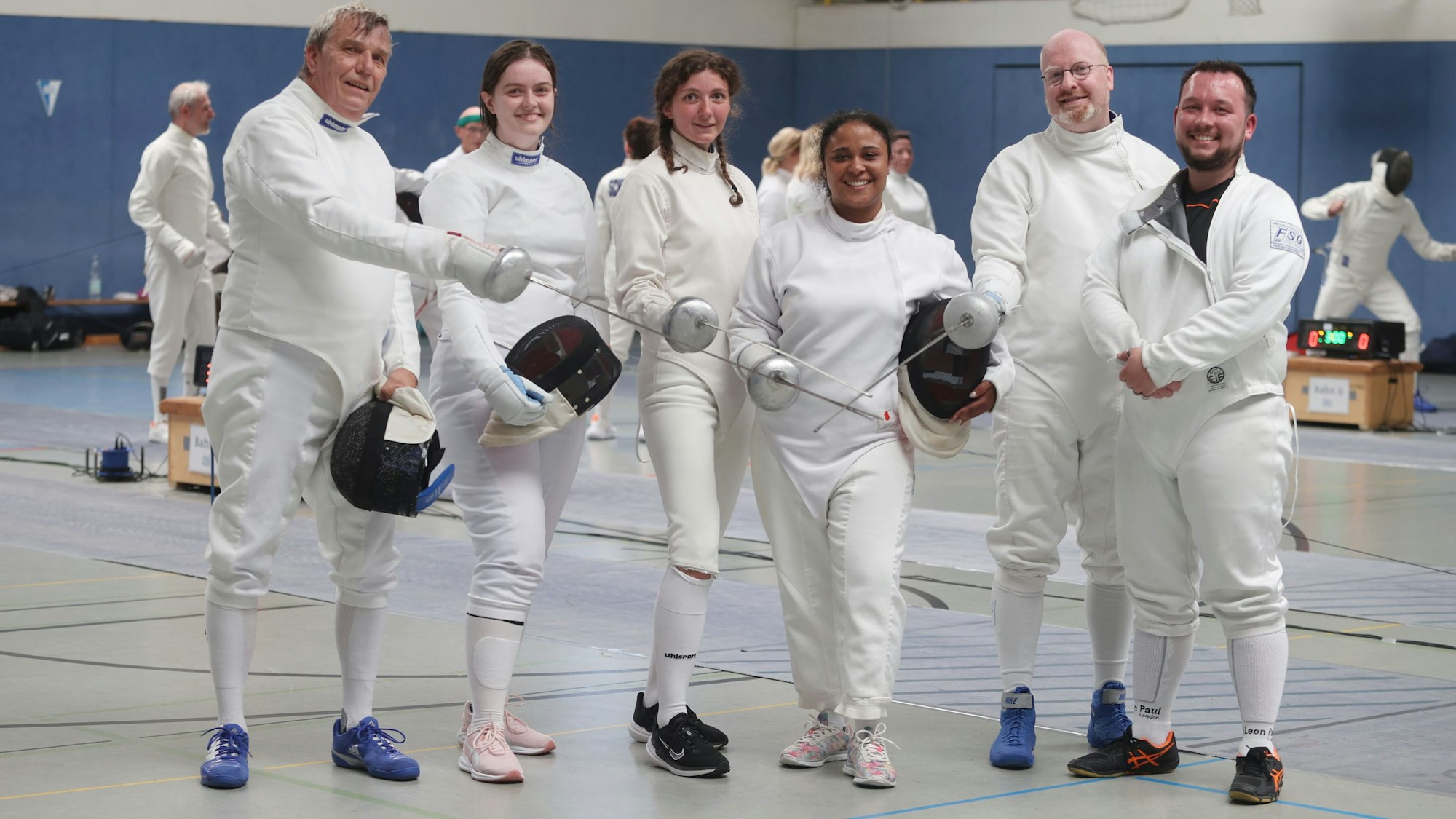 Sechs Fechterinnen und Fechter posieren mit ihren Degen für ein Foto.