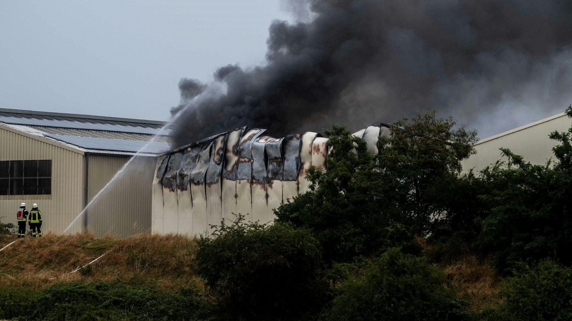 Schwarzer Rauch steigt aus einer Halle.