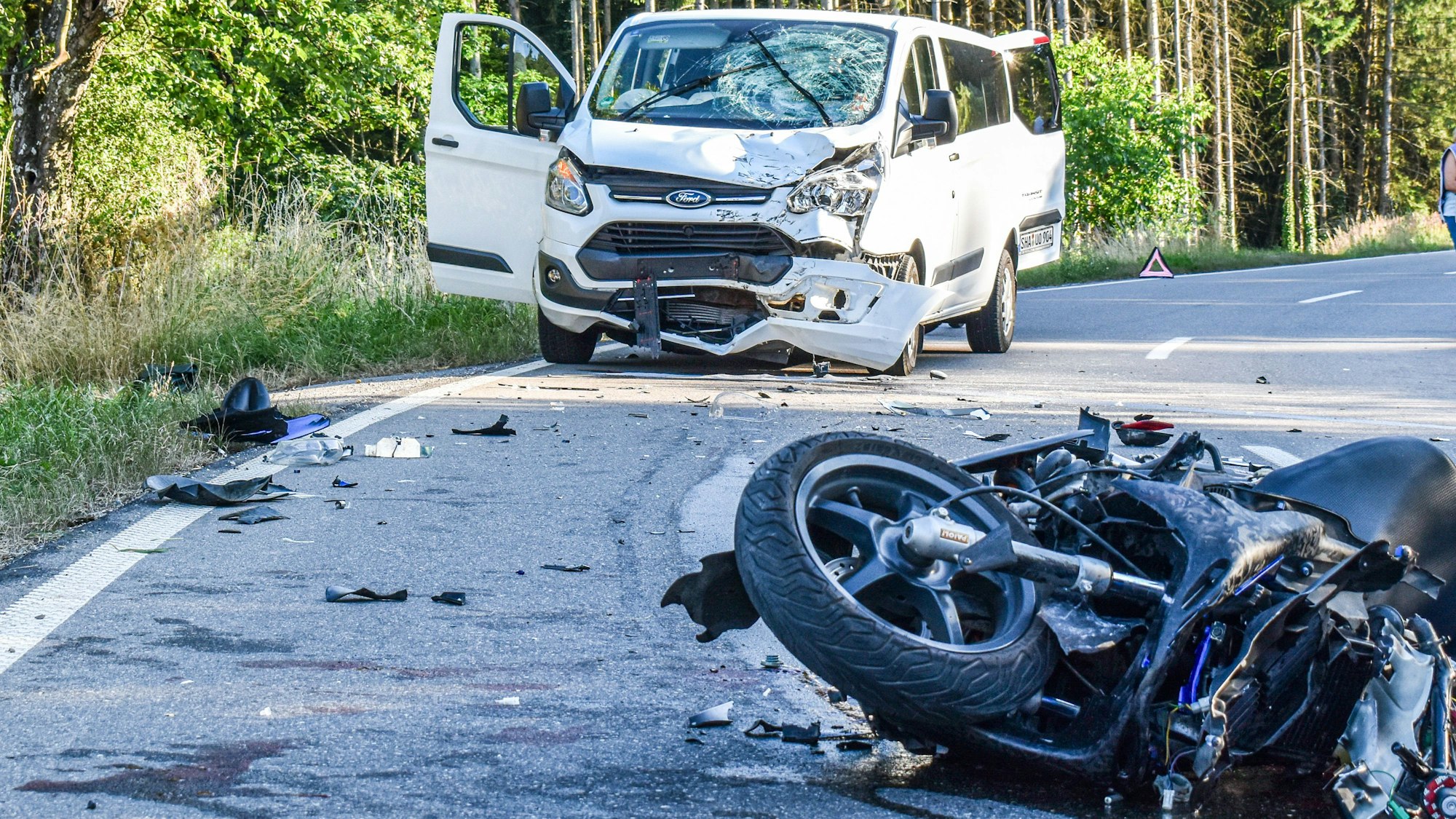 Ein schwer beschädigte Auto und ein Motorrad liegen und stehen an einer Unfallstelle auf der Bundesstraße B298. (Symbolbild)
