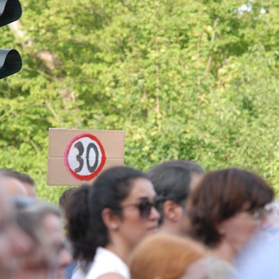 Mehrere Hundert Menschen nahmen im Sommer 2025 in Hürth an der Mahnwache für die beiden Menschen teil, die bei dem Verkehrsunfall ums Leben gekommen waren. Auf einem Schild war auch die Forderung nach Tempo 30 zu sehen.