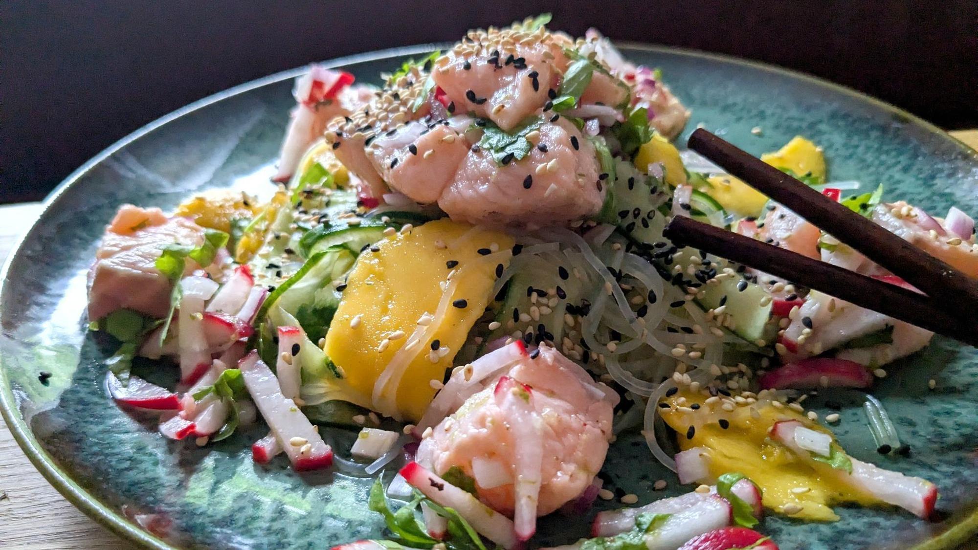 Der Glasnudelsalat mit Lachs-Ceviche wird mit gerösteten weißen und schwarzen Sesamkörnchen getoppt.