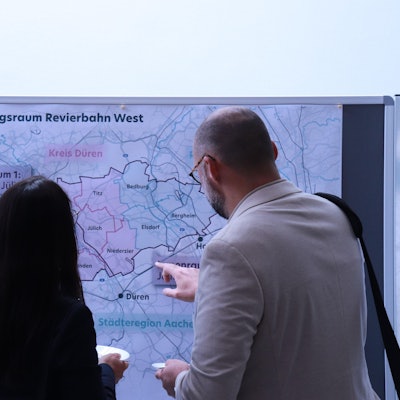 Eine Frau und ein Mann stehen vor einer Karte des Rheinischen Reviers.
