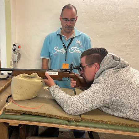 Ein Besucher schießt unter Aufsicht mit einem Kleinkalibergewehr.