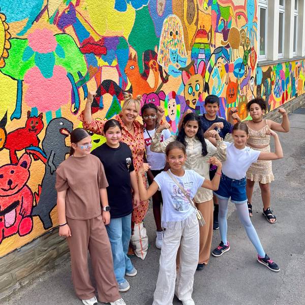 Kinder und Künstlerin vor einer bunten Wand