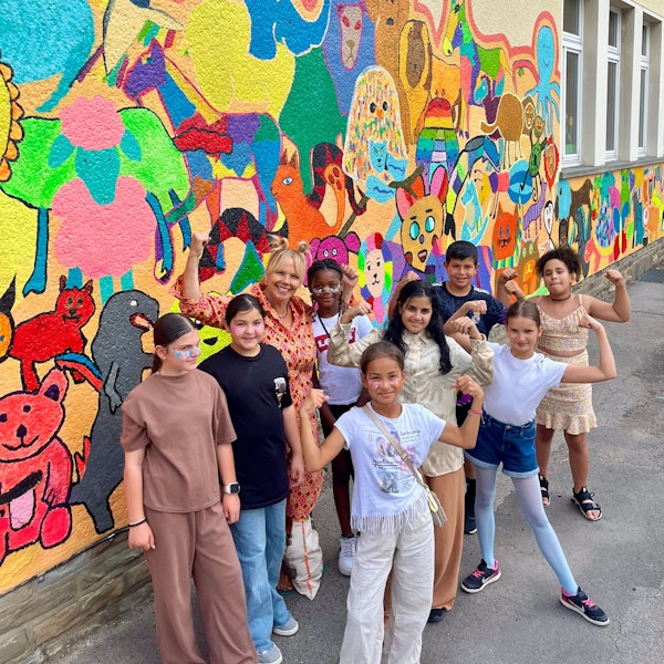 Kinder und Künstlerin vor einer bunten Wand