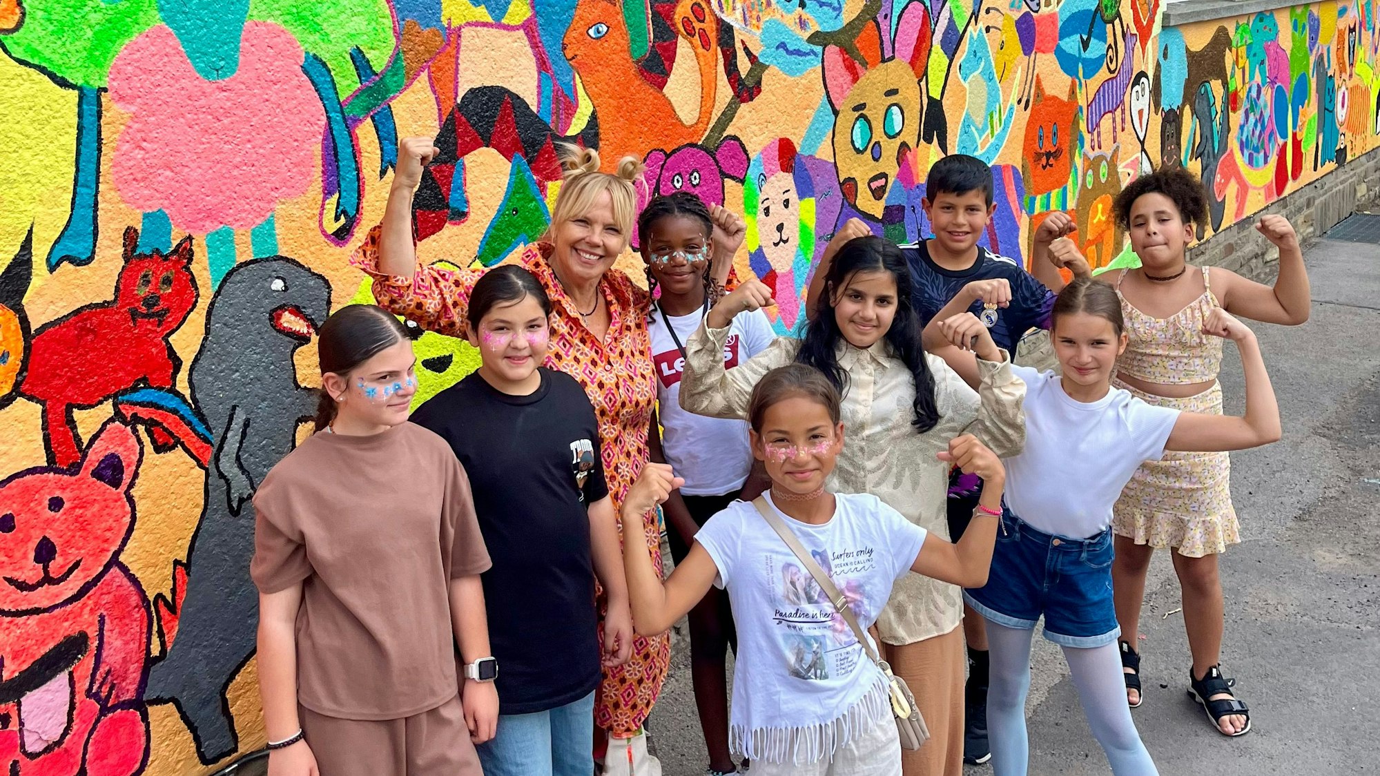 Kinder und Künstlerin vor einer bunten Wand