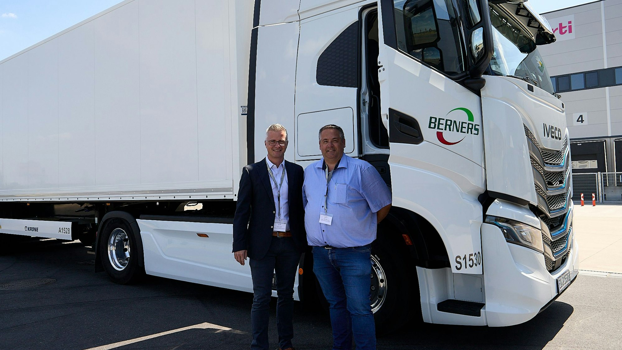 Zwei Männer stehen vor einem E-Truck, dessen Beifahrertür geöffnet ist.