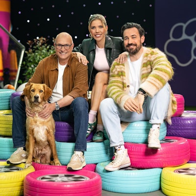 Das Kommentatoren-Duo Jan Köppen (r.) und Frank ‚Buschi‘ Buschmann mit der neuen Field-Reporterin Victoria Swarovski und Hündin Pebbles im „Top Dog“-Set.