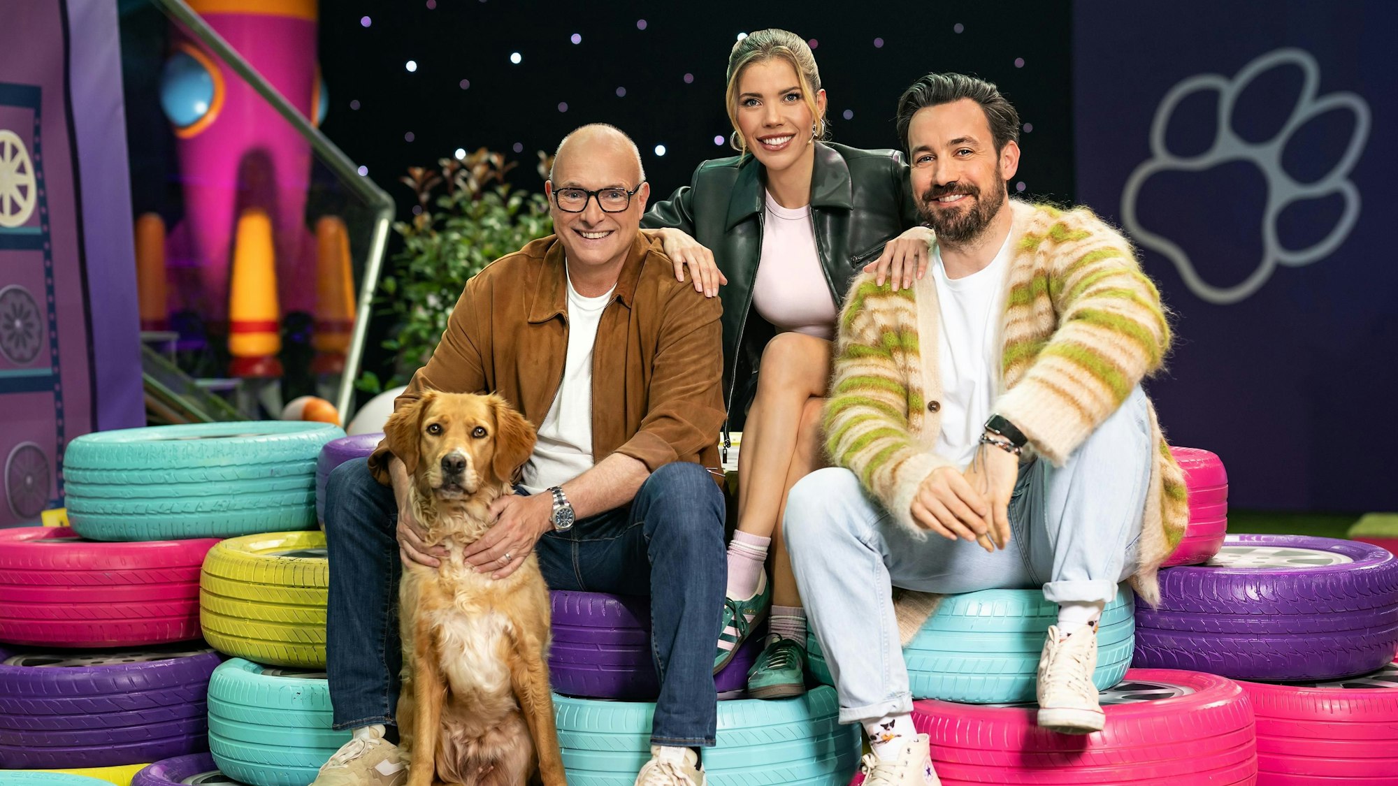 Das Kommentatoren-Duo Jan Köppen (r.) und Frank ‚Buschi‘ Buschmann mit der neuen Field-Reporterin Victoria Swarovski und Hündin Pebbles im „Top Dog“-Set.