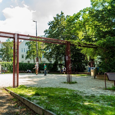 Ein Schotterplatz ist zu sehen, Leute spielen darauf Boule.