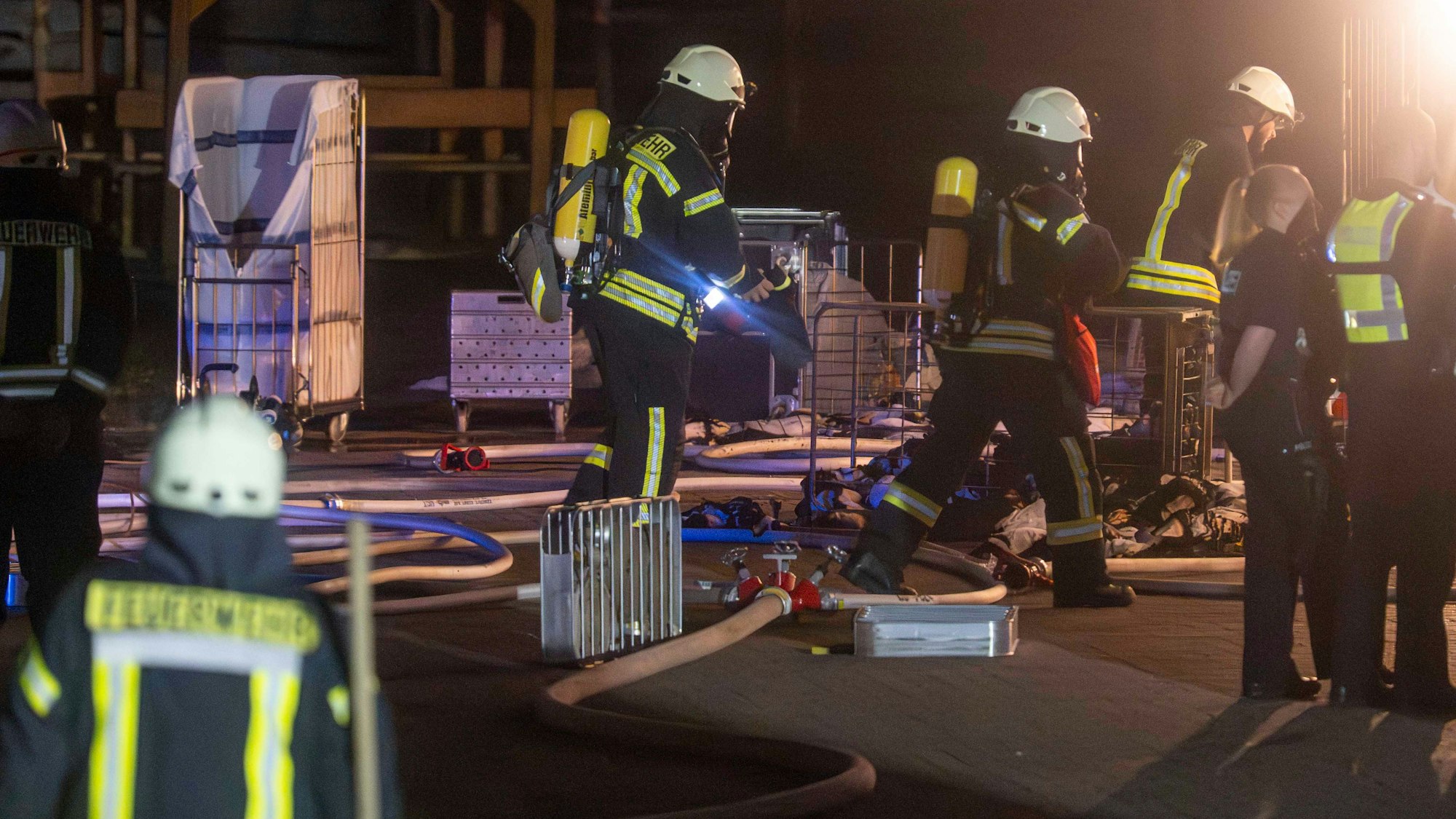Das Bild zeigt einige Feuerwehrleute an der Einsatzstelle. Sie tragen Atemschutzmasken.