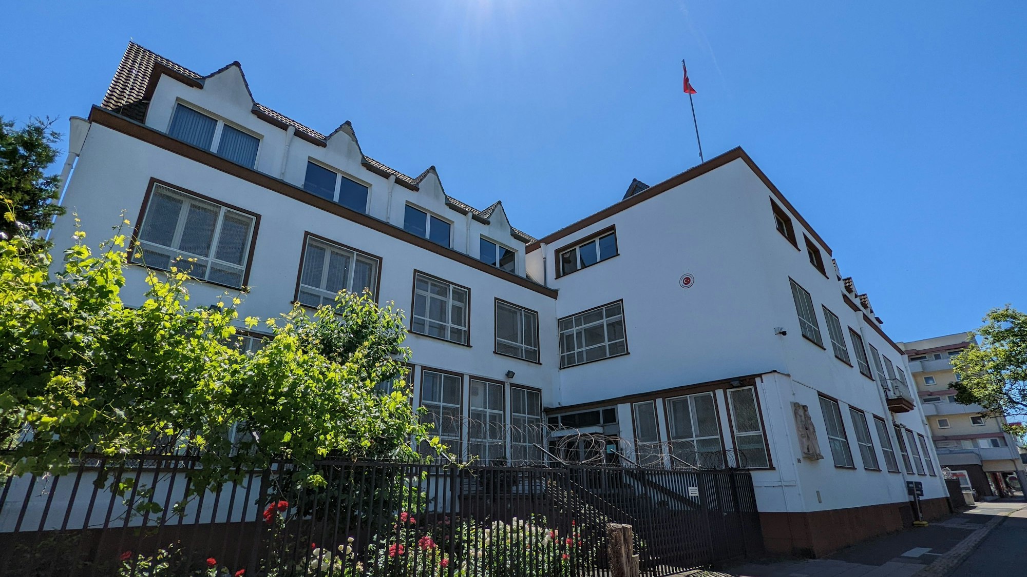 Ein großes Gebäude mit Türkei-Flagge auf dem Dach ist bei strahlendem Wetter zu sehen.