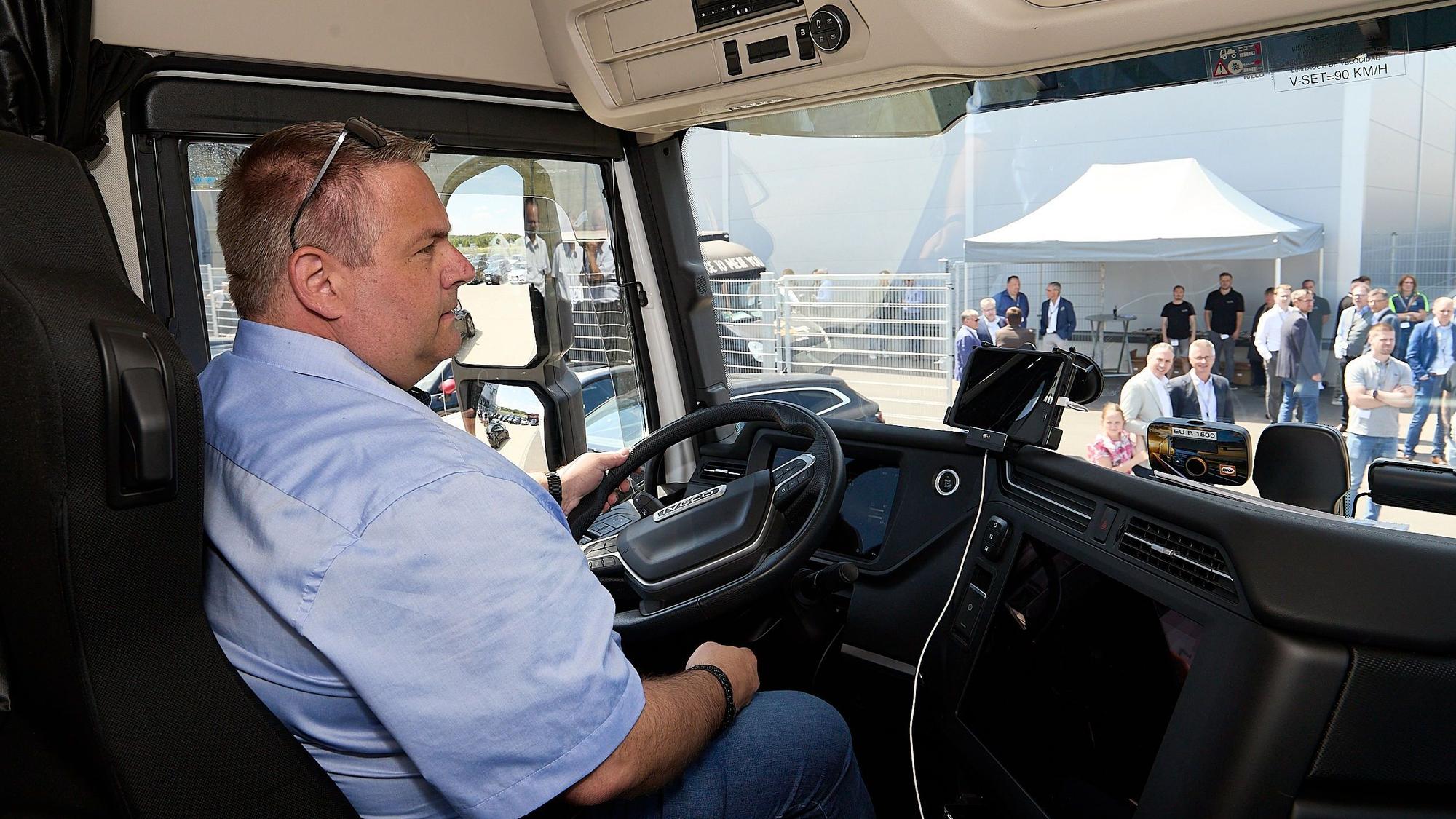 Fuhrparkleiter Daniel Kyll sitzt hinter dem Steuer des E-Trucks und hat die Sonnenbrille hochgeschoben.