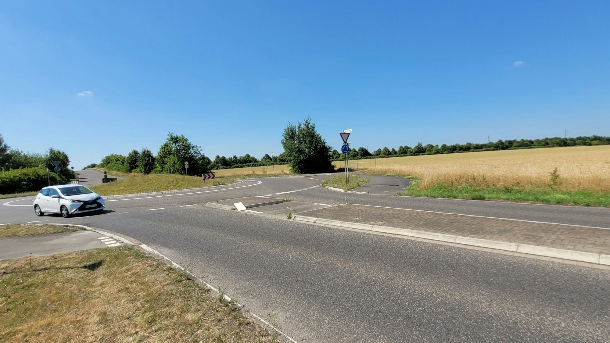 Ein Auto fährt in einem Kreisverkehr, in der Mitte stehen Fahnen.