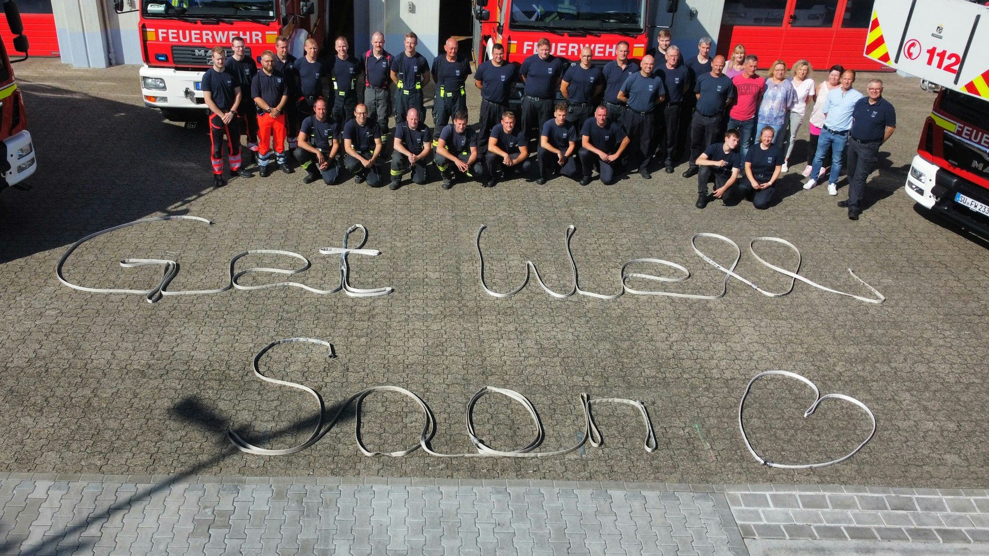 Die Schicht des bei einem Einsatz als Rettungssanitäter an der Stadthalle Troisdorf angegriffenen Feuerwehrmann legte aus Schläuchen ein ‚Get Well Soon‘ an der Feuerwache in Sieglar.