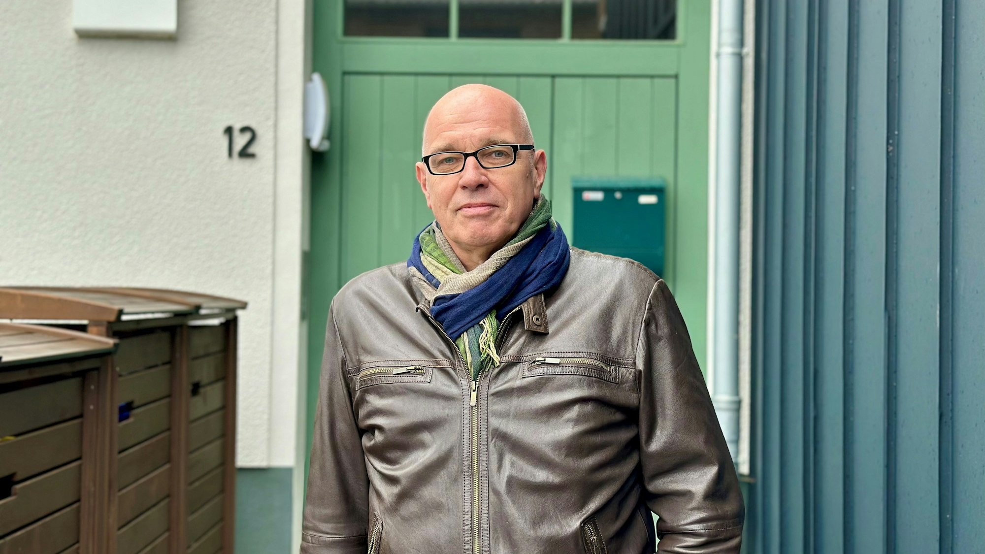 Ein Mann steht vor einer grünen Tür.