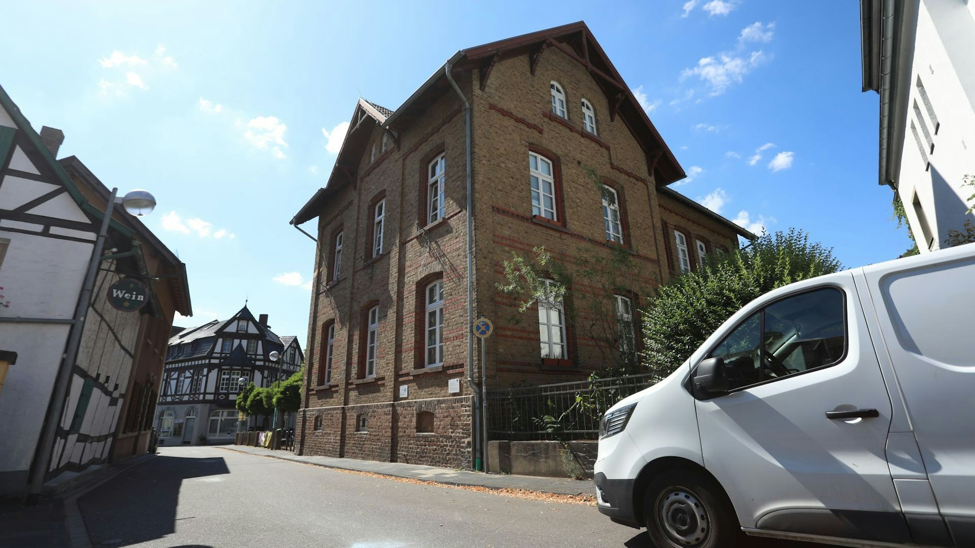 Ein altes Backsteingebäude, davor fährt ein weißer Lieferwagen über die Straße.