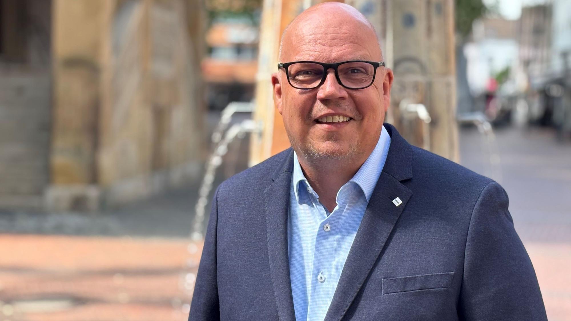 Auf dem Bild ist der Bürgermeisterkandidat Uwe Tietz in einem blauen Anzug zu sehen.