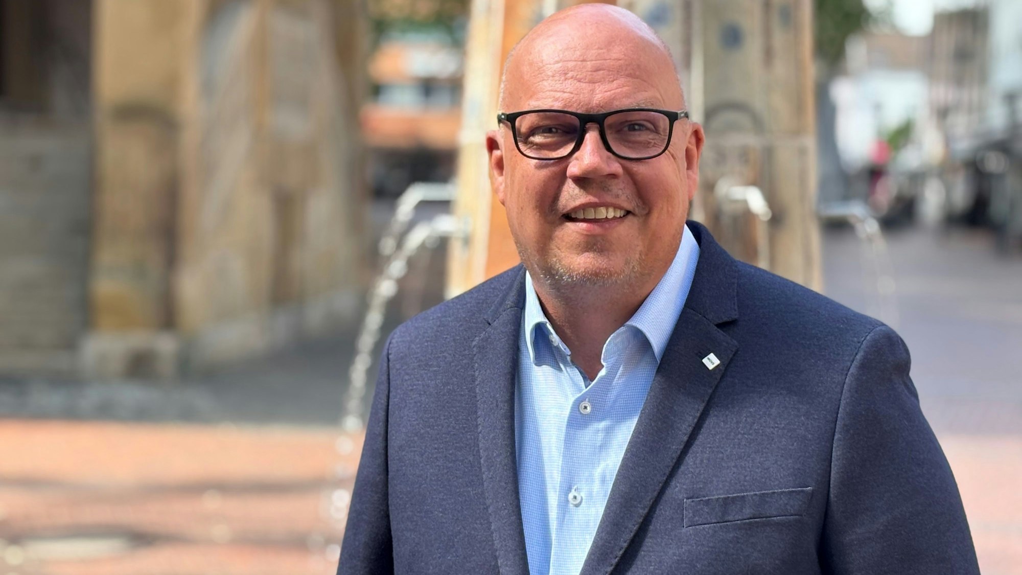 Auf dem Bild ist der Bürgermeisterkandidat Uwe Tietz in einem blauen Anzug zu sehen.