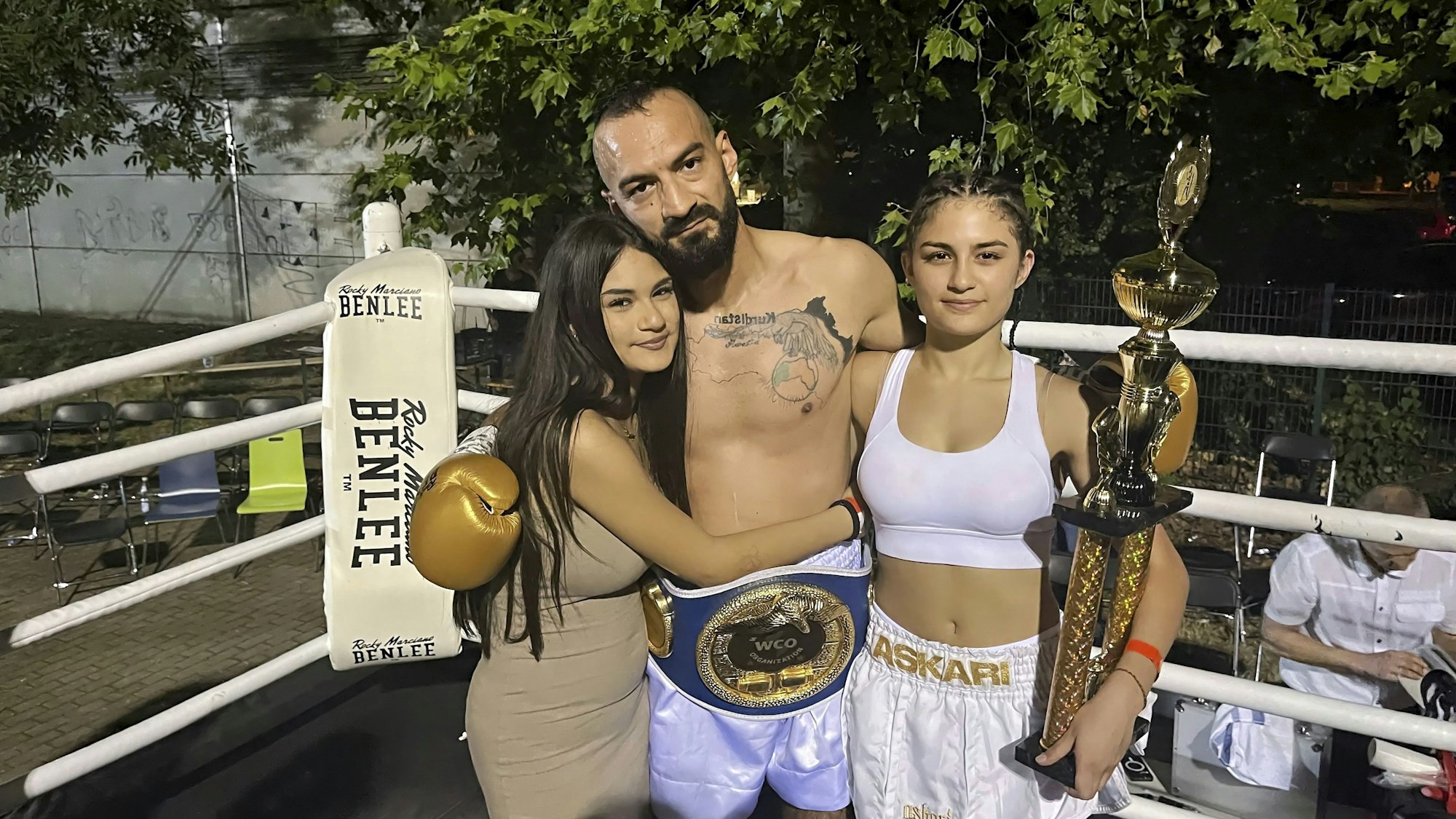 Der Boxer Botan Göcmen steht im Ring und hat seine Töchter Medya (l.) und Awesta im Arm-