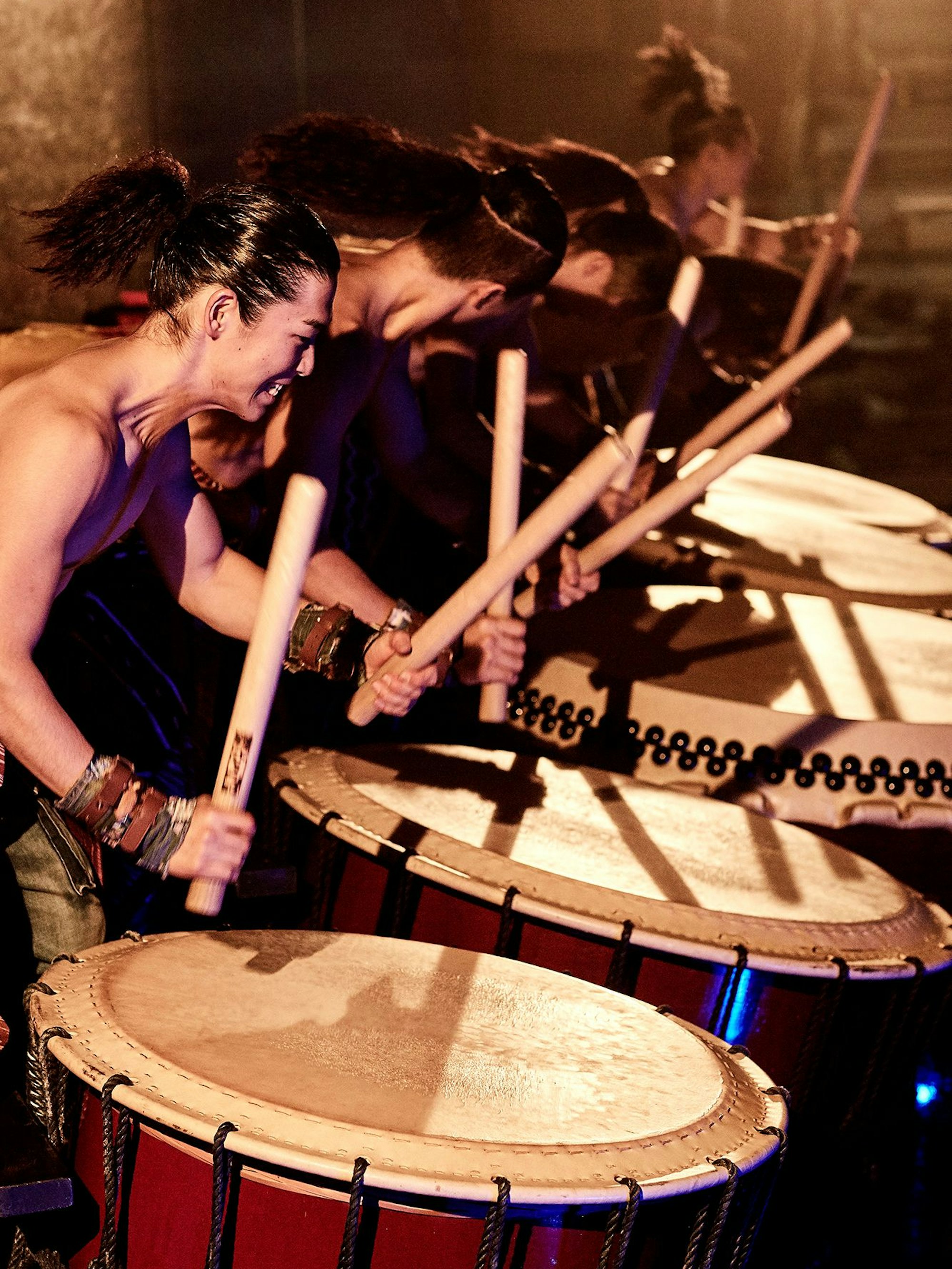 Fünf Trommler in einer Reihe bearbeiten stehende Trommeln mit Schlagstöcken.