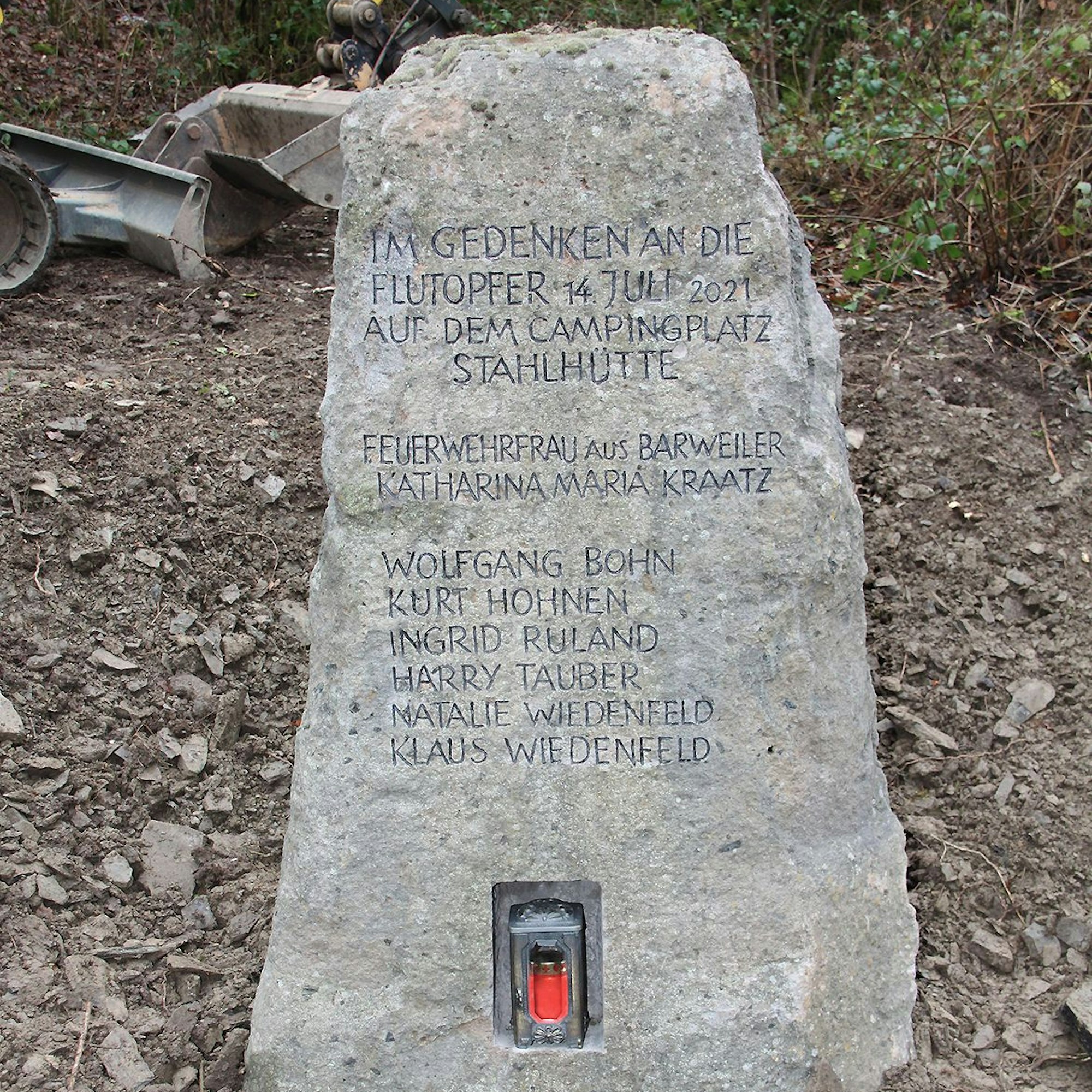 In einem Gedenkstein ist eine Grabkerze eingelassen. Auf dem Basaltstein stehen die Namen der Verstorbenen.