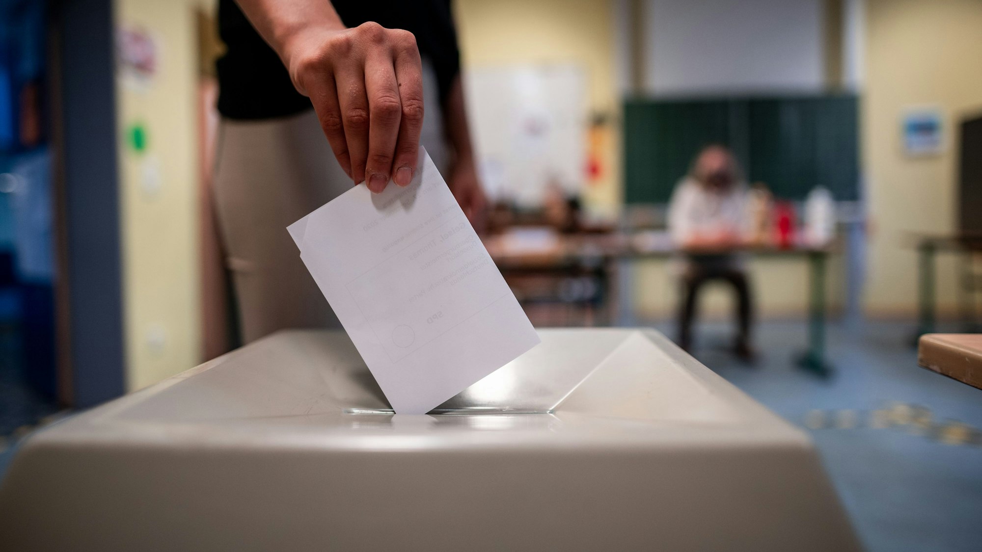 Eine Frau wirft einen Wahlzettel in eine Wahlurne.