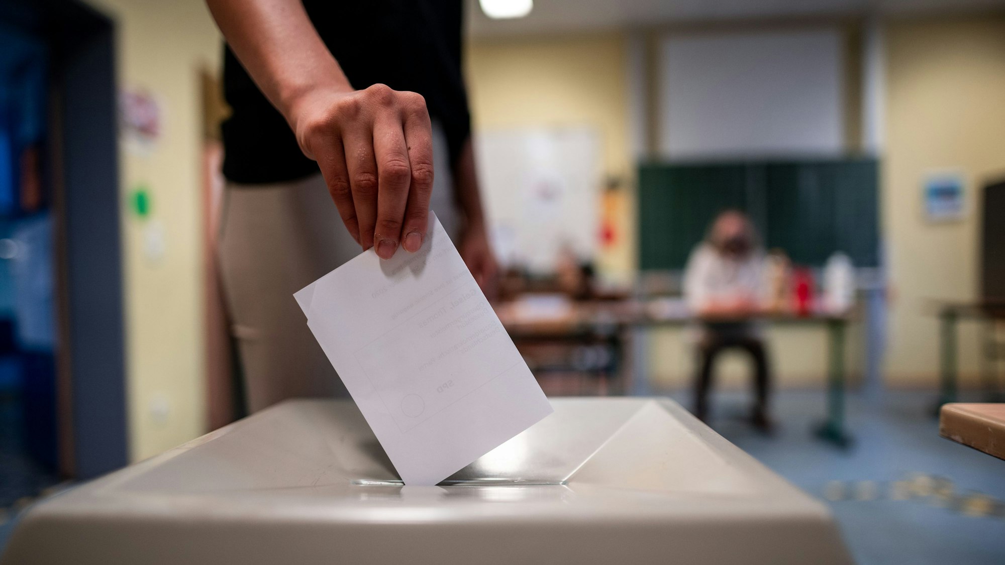 Eine Frau wirft einen Wahlzettel in eine Wahlurne.